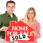 couple with home sold sign